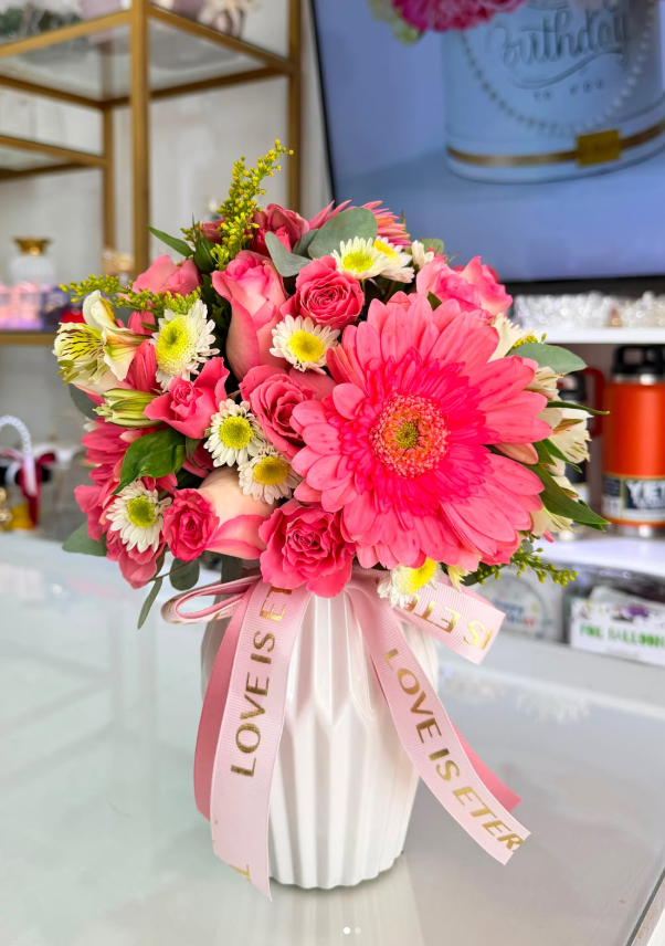 Arreglo en jarrón blanco con gerberas coral y mini rosas